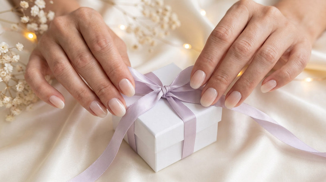Mains qui nouent un ruban lilas autour d'une petite boîte cadeau blanche